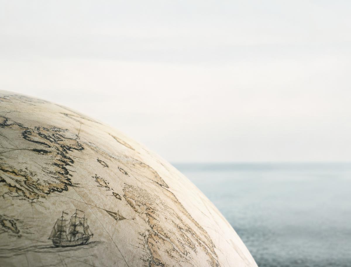 A detail of an antique globe against a soft sea horizon